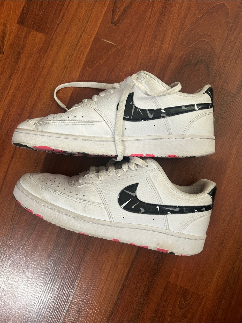 Nike White Low-Top Sneakers with Black Patterned Swoosh and Pink Outsole Accents